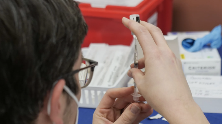 person filling syringe with vaccine