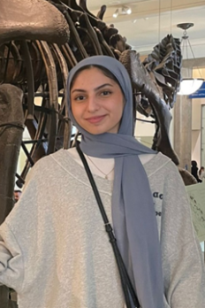 photo of Maya Salameh standing in front of dinosaur fossil