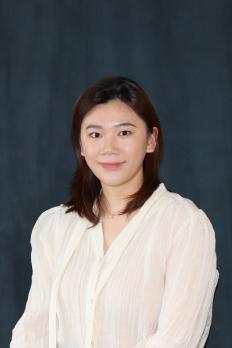 profile photo of Meifan standing in front of dark curtain