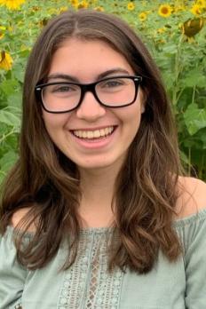 photo of Myah standing in front of sunflowers