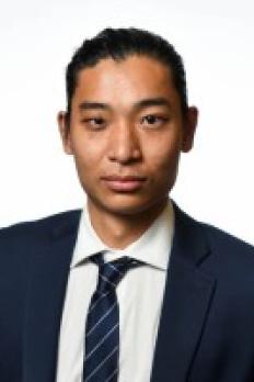 headshot of Sam in a suit