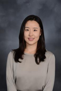 headshot of Sandra in front of blue grey background
