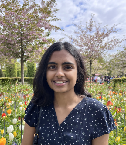 Anushka standing in front of trees and field