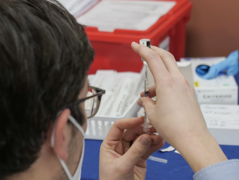 person filling syringe with vaccine